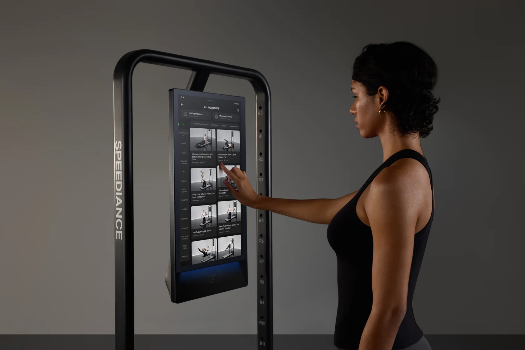 Una donna seleziona un esercizio sul touchscreen di Gym Monster 3