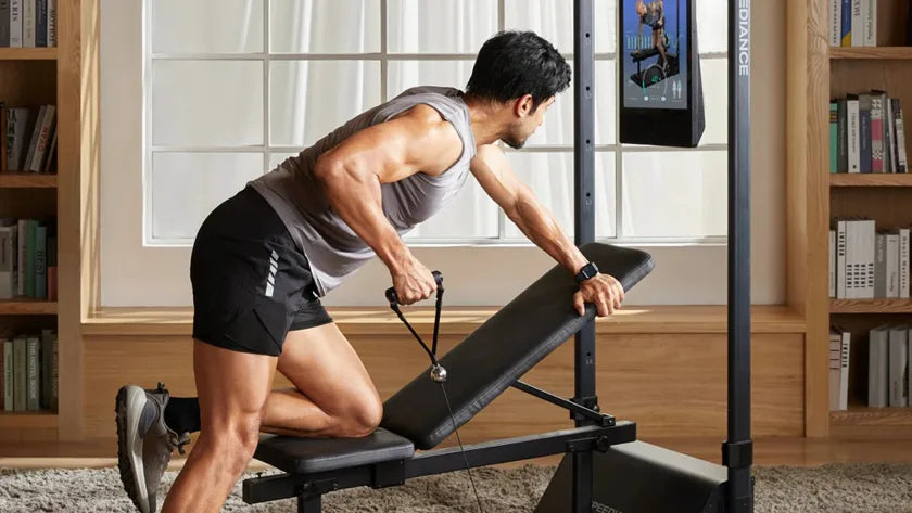 Ein Mann trainiert zuhause an Gym Monster 3 in einem hellen, bücherreichen Wohnzimmer