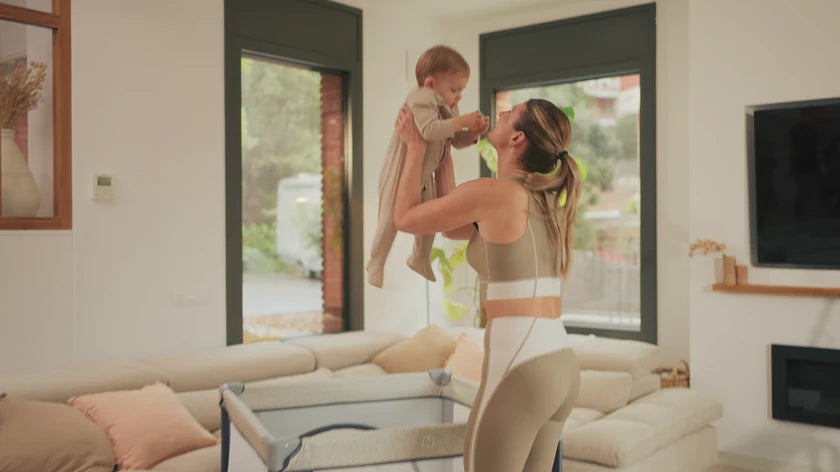 Eine Mutter hebt ihr Baby im Wohnzimmer hoch, zuhause